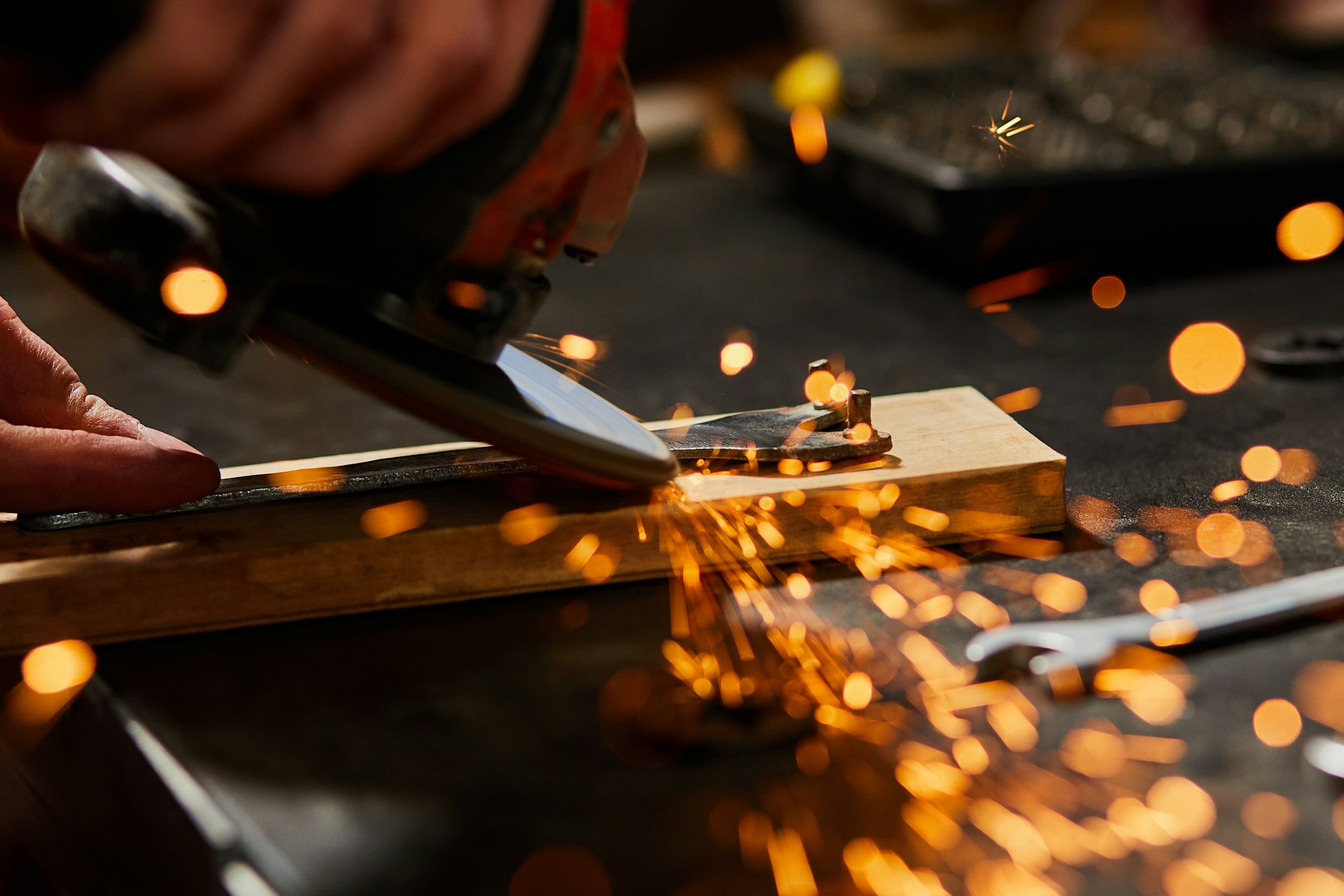 Close up Locksmith works with grinder machine, fly bright sparks.